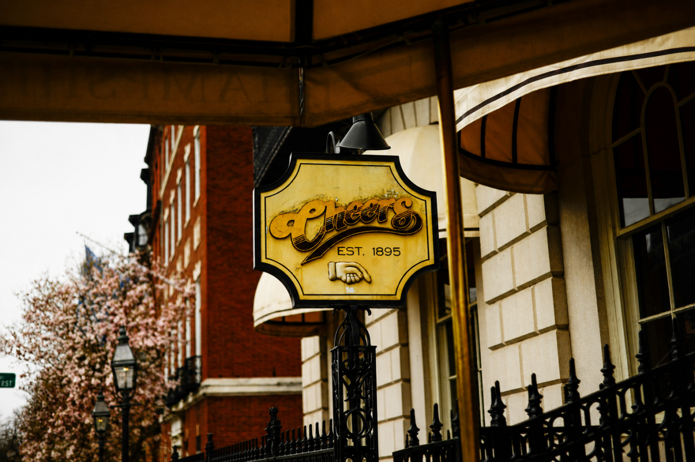 The iconic Cheers bar sign in Boston, reading 'Cheers Est. 1895', hanging over the entrance