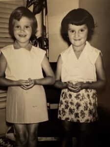 Nicole and her sister Aurélie as young girls, dressed up and standing side by side